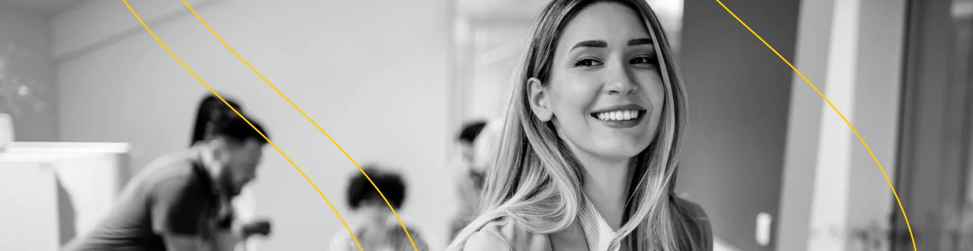 Uma imagem em preto e branco que retrata uma mulher sorridente em primeiro plano, destacando sua expressão alegre e confiante. Ao fundo, uma equipe dedicada está trabalhando em conjunto, transmitindo uma atmosfera de colaboração e produtividade.