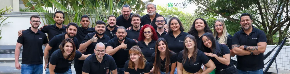 Equipe reunida ao ar livre, sorrindo e em clima descontraído, reforçando espírito de equipe.