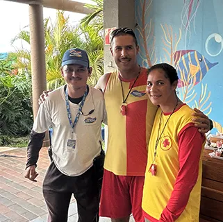 Três colaboradores lado a lado, sorrindo.