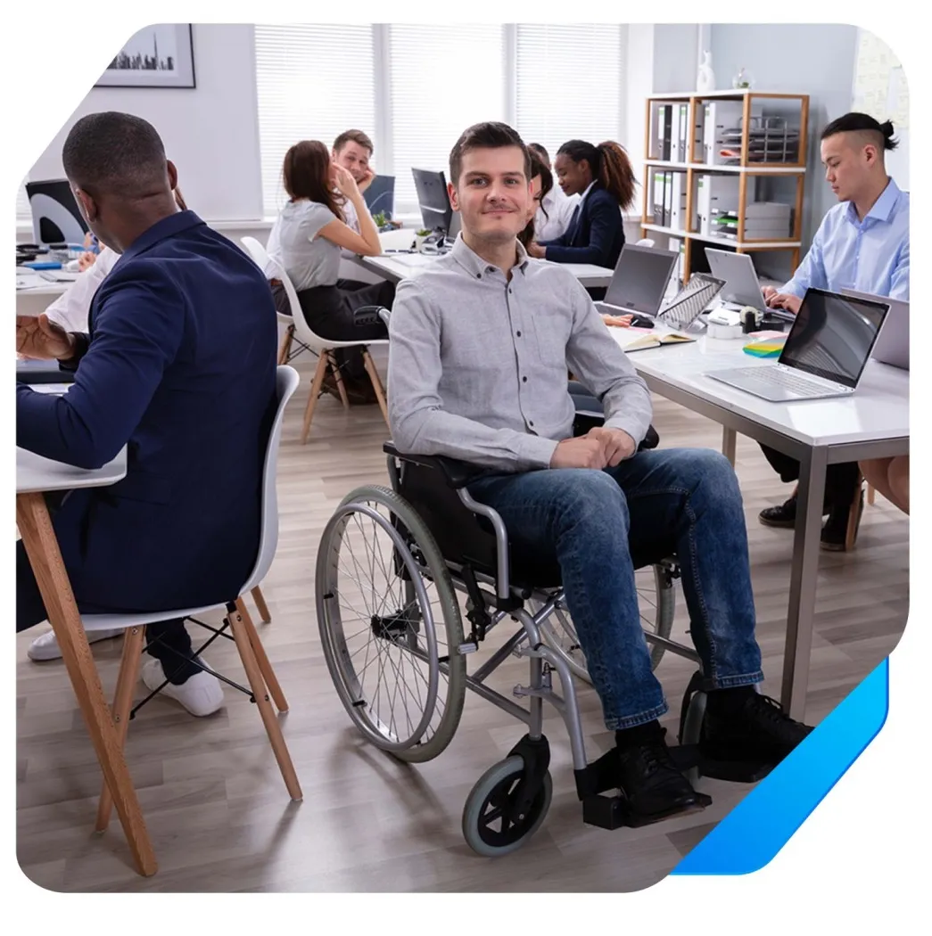 Foto de cadeirante de camisa social e calça jeans no ambiente de trabalho.