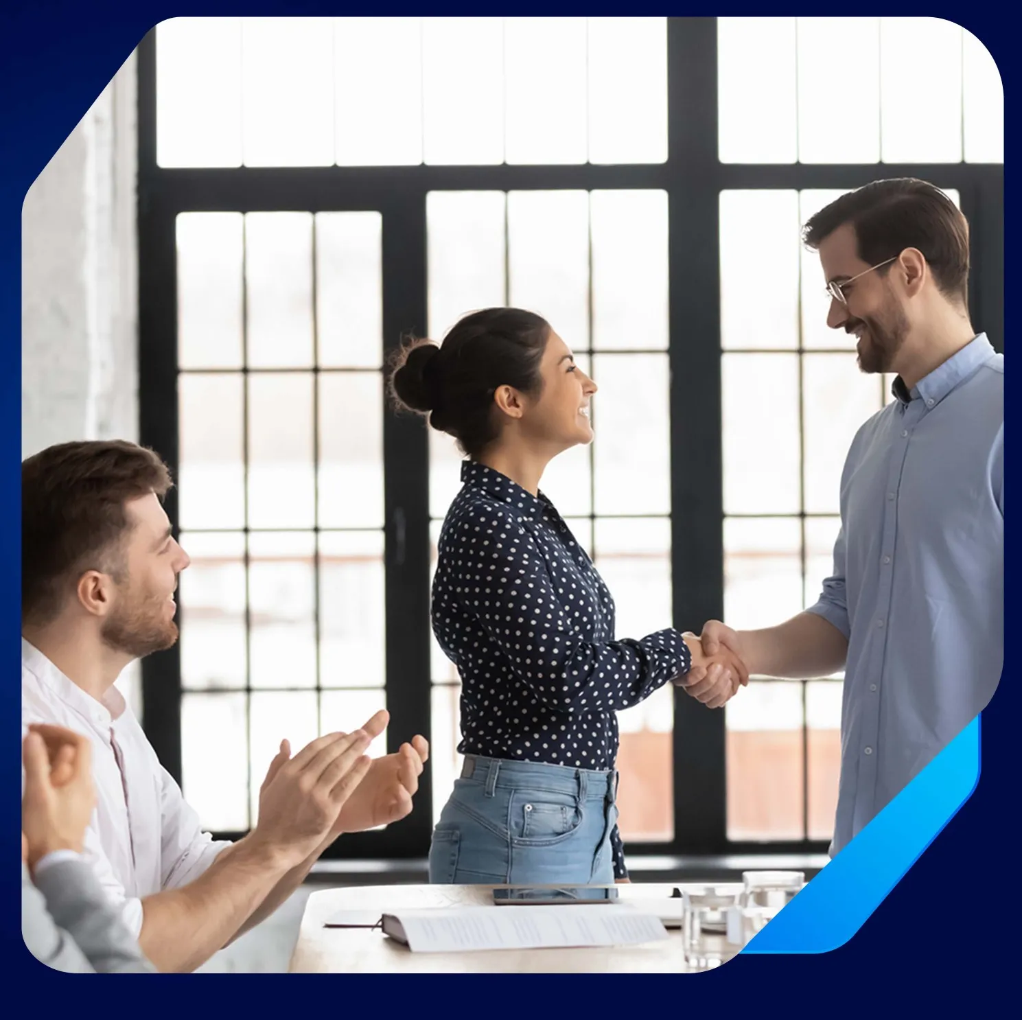 Foto de ambiente de trabalho com um homem e uma mulher brancos se cumprimentando.