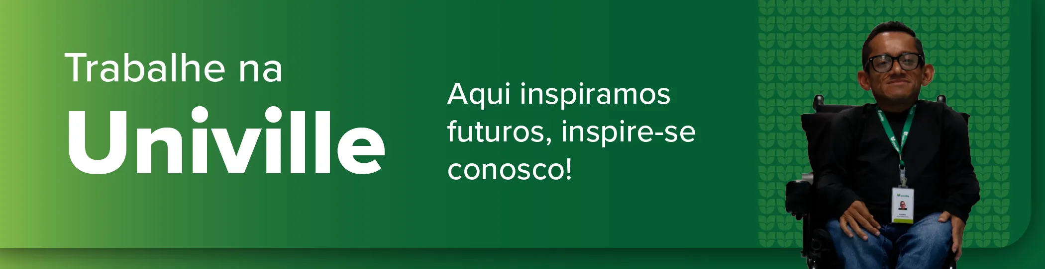Um banner de fundo verde que convida a trabalhar na Univille. À esquerda, o texto em branco diz: "Trabalhe na Univille. Aqui inspiramos futuros, inspire-se conosco!". À direita, há uma foto de um homem , sentado em uma cadeira de rodas. Ele usa óculos, camisa preta, calça jeans e um crachá da Univille no pescoço. O fundo atrás dele tem detalhes sutis da logomarca da Univille em tons verdes.