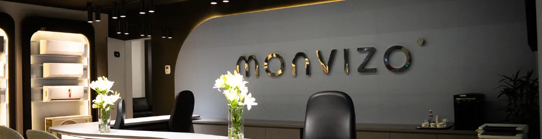 Imagem da loja interna da monvizo ar condicionado, em alta na parede a logo colada em metal brilhante, ao fundo exposição das máquinas a venda