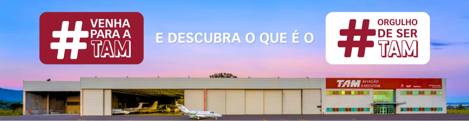 Fundo: Hangar da TAM da base de Jundiaí. A imagem possui dois retângulos, o primeiro é na cor bordô, escrito: "#Venha para a TAM". O segundo é na cor branca, escrito: "Orgulho de ser TAM".